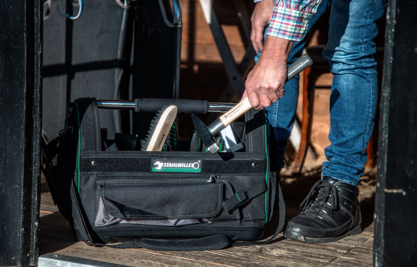 Man picking up a hammer from a STAHLWILLE tool bag